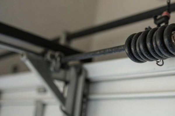Close-up of a worn garage door spring showing visible rust and tension loss